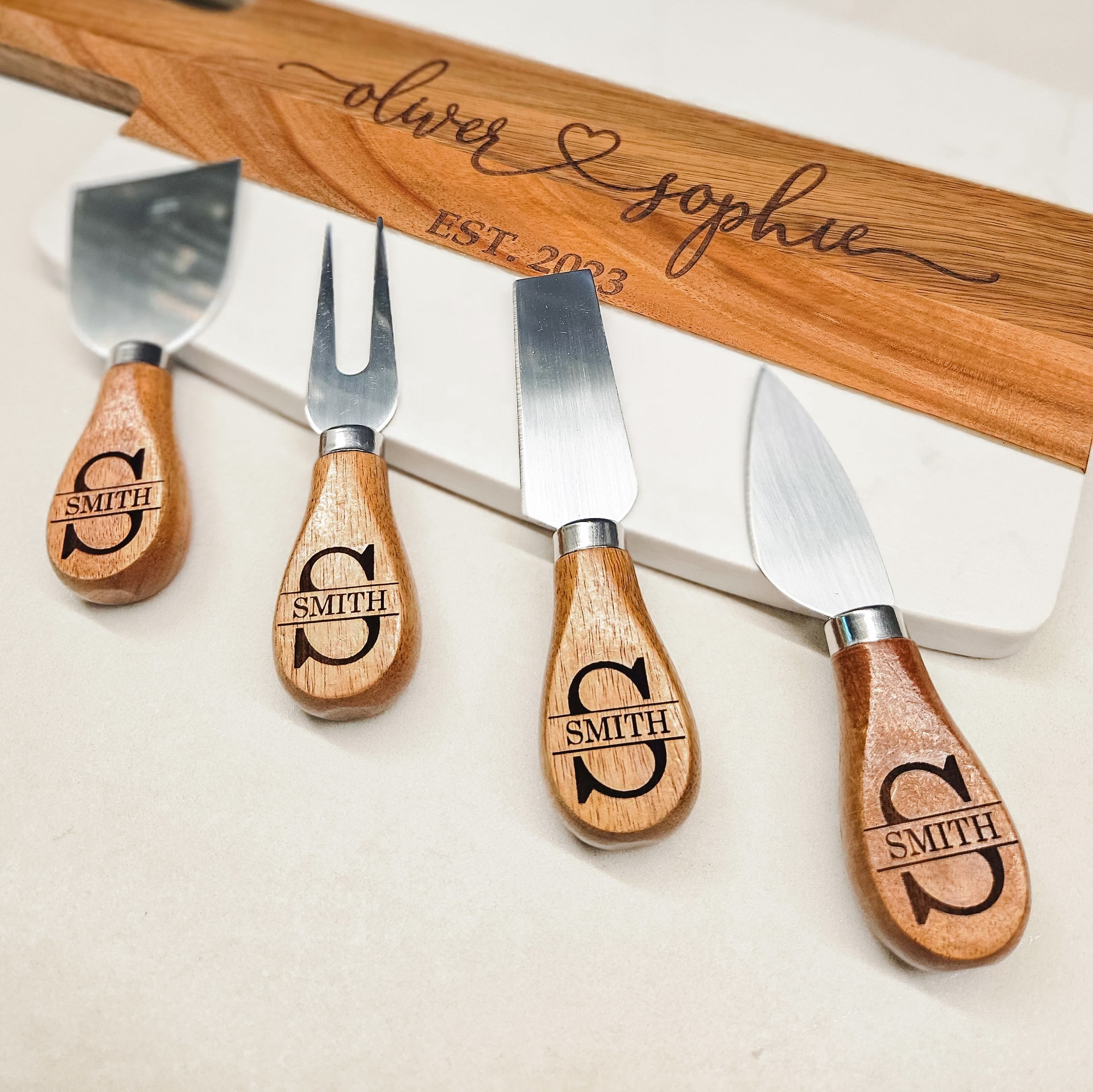 Cheese knives with acacia wood handles on a marble and wood chopping board