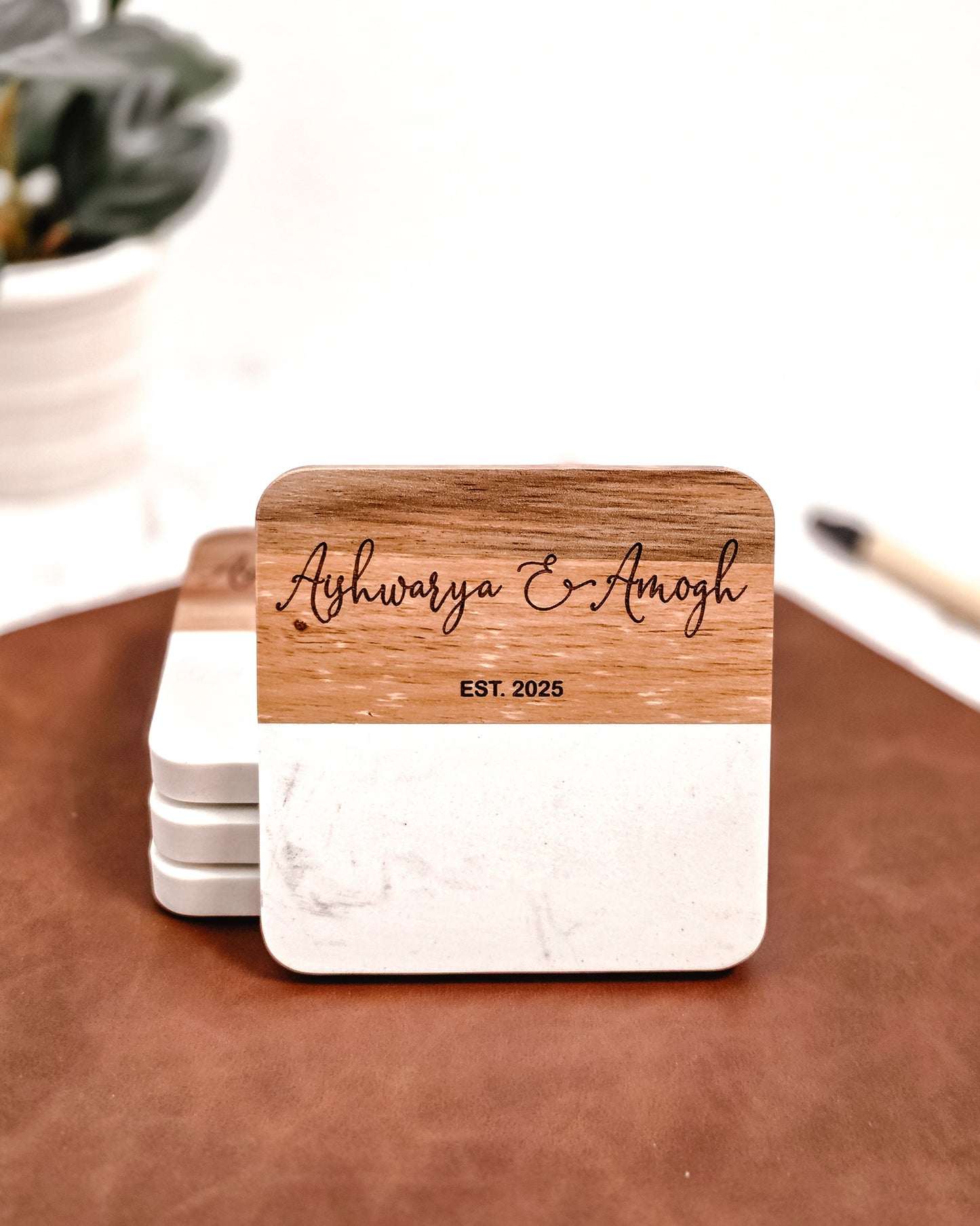 Wooden coaster with 'Ashwarya & Amogh' engraving on a marble coaster.